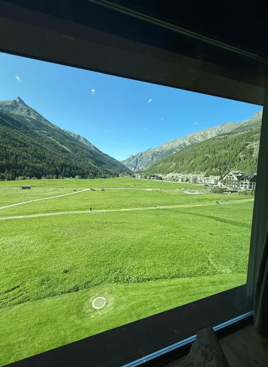 View from the hotel room window: a green Alpine valley with mountains beyond